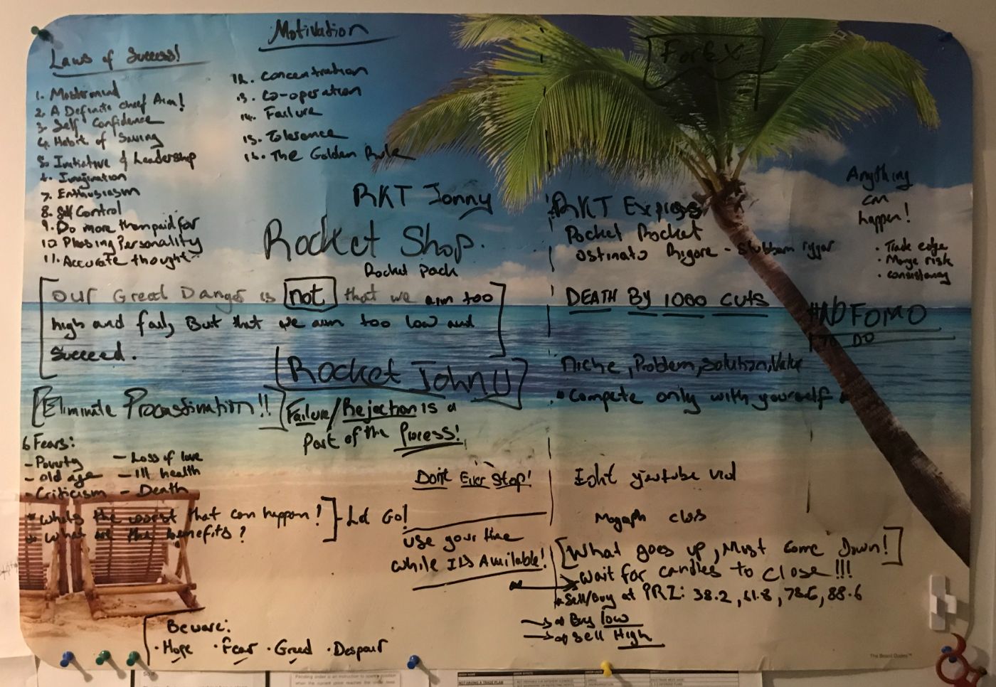 The original palm-tree island whiteboard, covered in handwritten goals, including a list of the Laws of Success